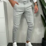 Muške sive karirane pantalone sa belim motivima, bočni pogled s rukom u džepu.