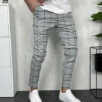 Karirane muške pantalone u svetlo sivoj boji sa tamno sivim/crnim motivima. Prednja strana.