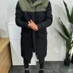 Muška zimska jakna u maslinastoj boji sa tamno sivim gornjim delom i kapuljačom. Obložena krznom iznuta. Prikaz zakopčane jakne sa prednje strane.