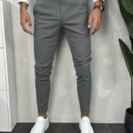 Elegantne muške pantalone u sivoj boji slim fit kroja uparene sa belim patikama i belom košuljom. Prikaz prednje strane.