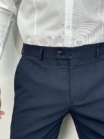 Elegantne muške pantalone sa duplim kopčanjem na prednjoj strani u teget boji, kroj slim fit. Prikaz gornjeg dela prednje strane izbliza.