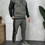 Muški maslinasto zeleni trenerka komplet s crnim prošivenim detaljima na rukavima i nogavicama, pogled sa strane.