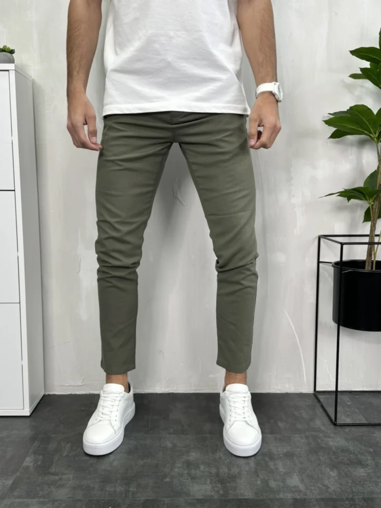 Muške pantalone u maslinasto zelenoj boji, slim fit kroj, model u belim patikama, prednji prikaz.