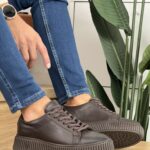 Muške elegantne kožne patike sa rebrastim đonom u braon boji. Slika kombinacije sa tamno plavim farmerkama.