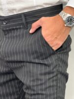 Detaljan prikaz prednjeg džepa i pojasa na elegantnim prugastim pantalonama.