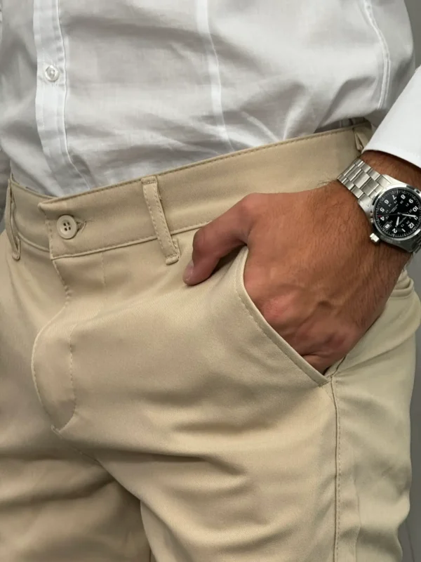 Detaljan prikaz prednjeg džepa i pojasa na bež elegantnim pantalonama.