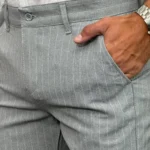 Blizak pogled na tkaninu sivih pantalona sa belim prugama, ističući kvalitet materijala i detalje kroja.