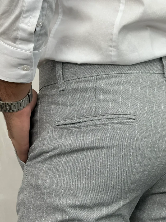 Detaljan prikaz bočnih džepova sivih pantalona sa belim prugama, elegantan dodatak za moderan outfit.