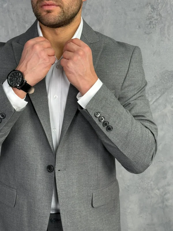 Tamno sivi muški sako sa jednostrukim kopčanjem, detaljan prikaz izbliza sa naglaskom na rukave i dugme na pojasu.