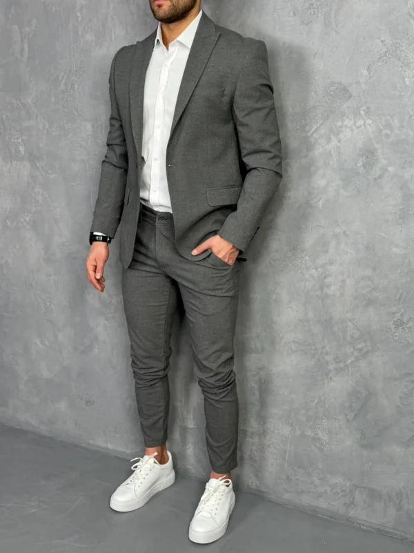 Tamno sivi muški sako sa jednostrukim kopčanjem, prikaz celog outfita u kombinaciji sa belom košuljom i patikama.